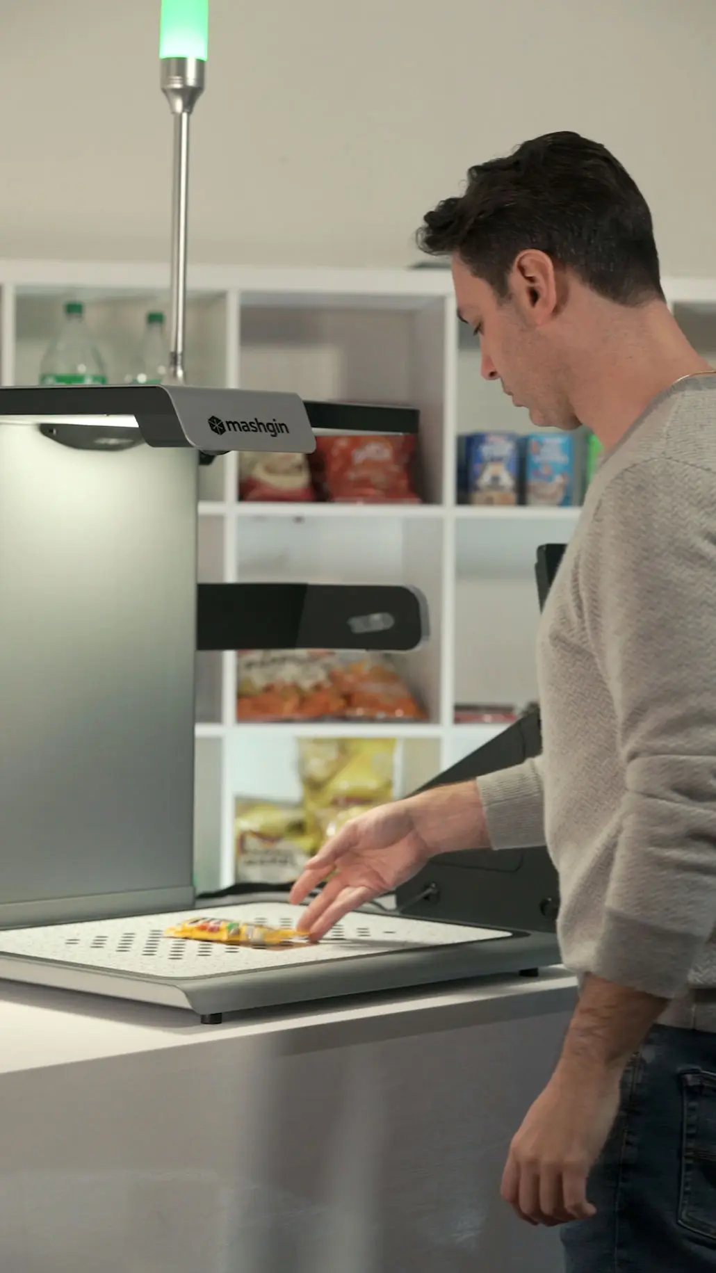 A fellow places a packet of peanut M&Ms on a Mashgin kiosk